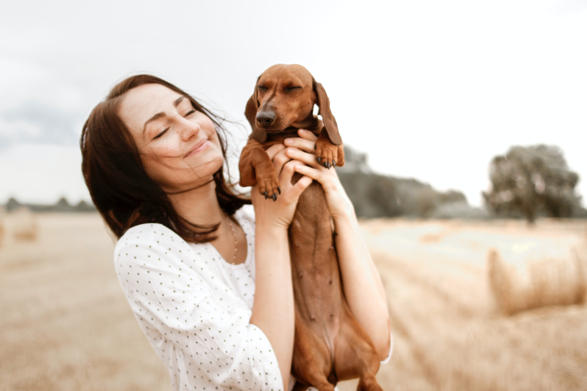 Donna che solleva in braccio con affetto un cane bassotto.